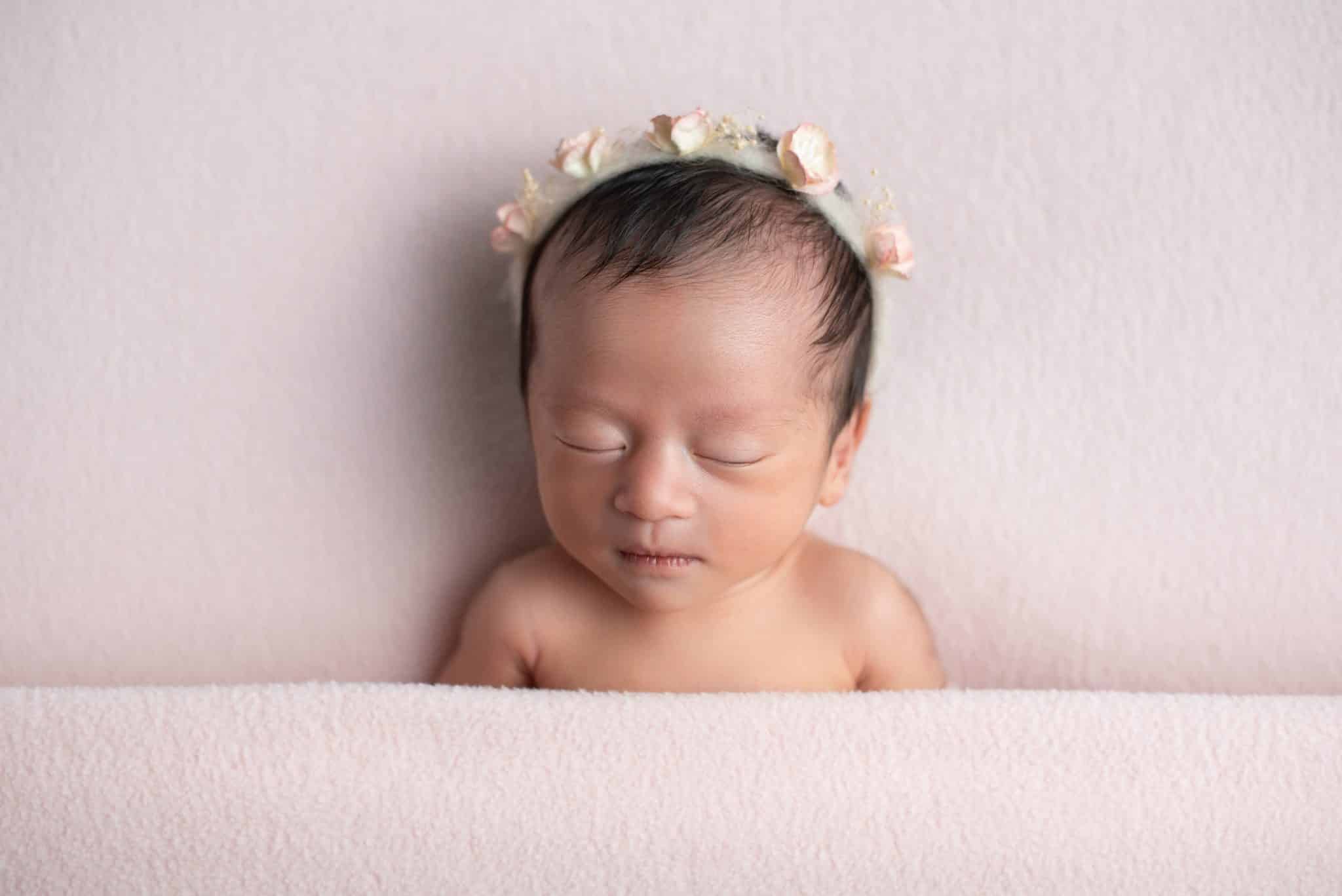 Peacefully sleeping newborn girl with floral headband captured by a Toronto newborn photographer