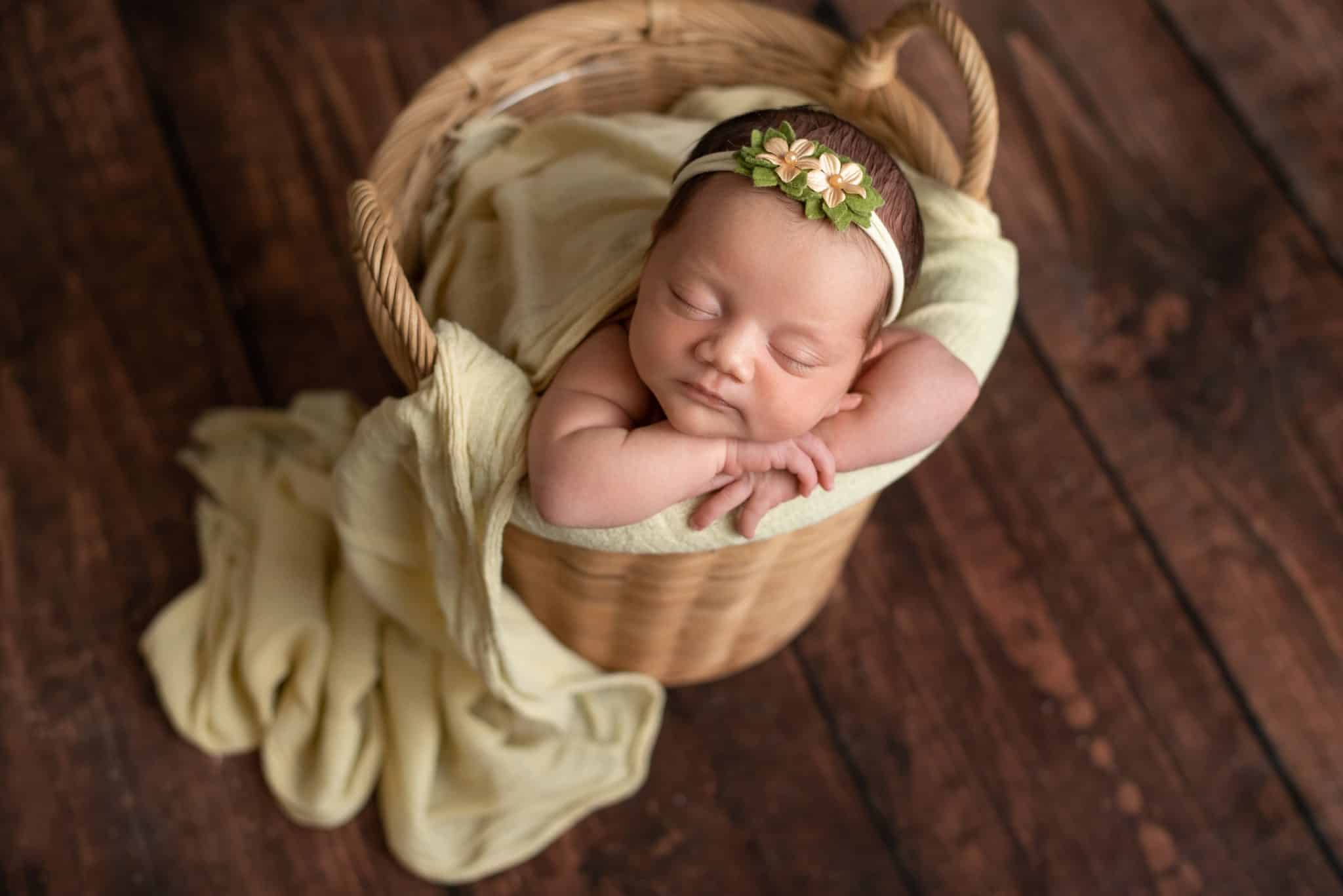 Newborn photoshoot of the baby girl in basket with flowers