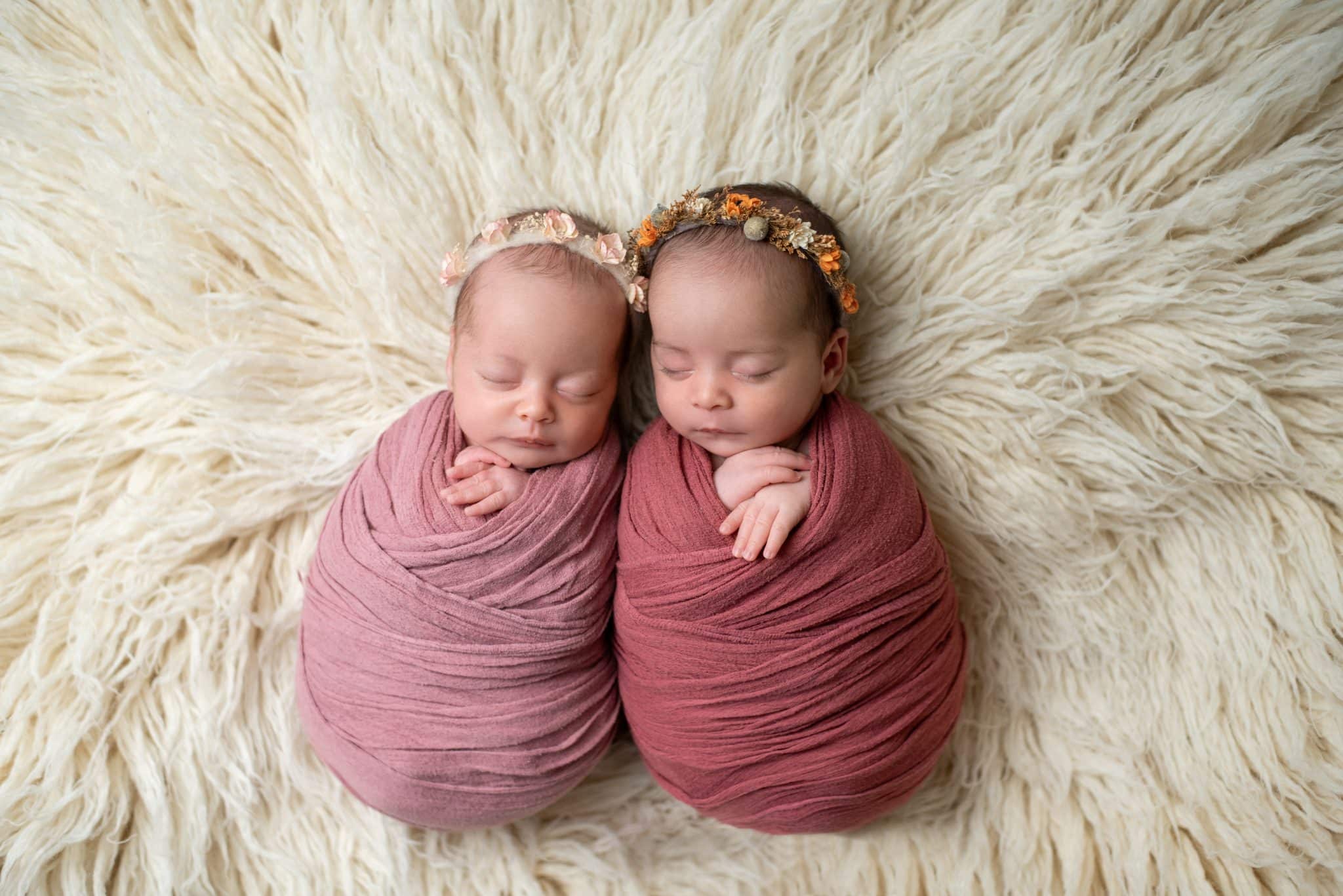 Sleeping newborn twins wrapped in soft pink swaddles during a Toronto newborn photography session