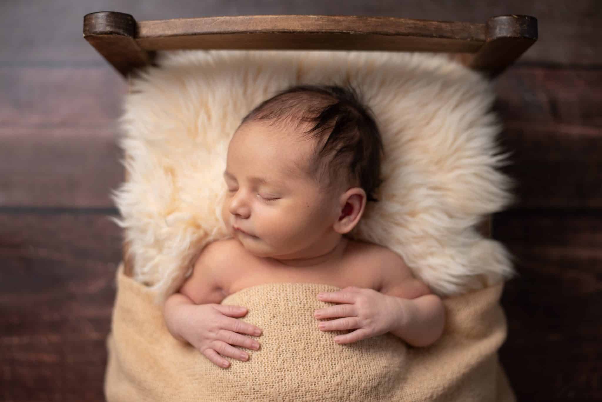 Newborn photoshoot Toronto – baby peacefully sleeping in rustic basket with neutral tones