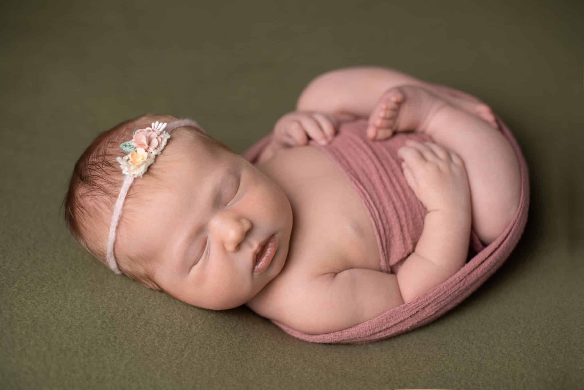 Sweet baby girl wrapped in soft pink fabric during a natural newborn photography Toronto studio session