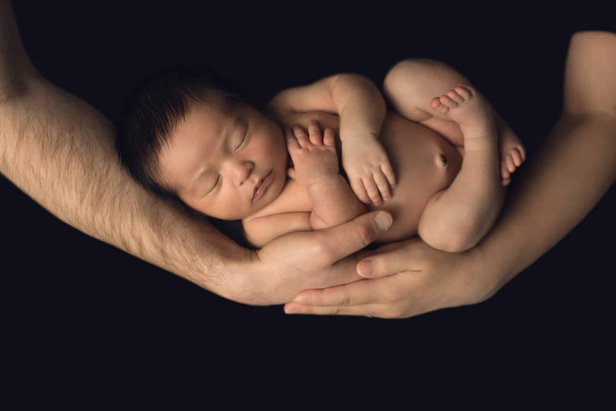 Newborn family photos Toronto – parents holding newborn baby in warm emotional portrait
