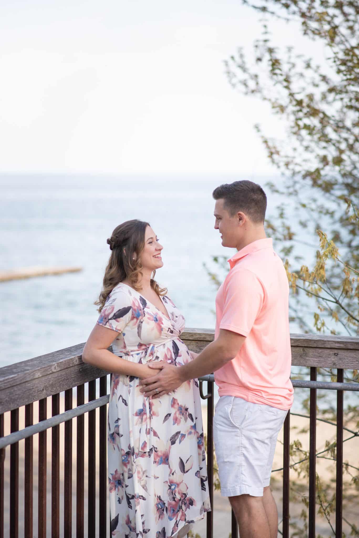 Romantic maternity couple photoshoot at lakeside lookout, pregnancy photography Toronto waterfront, candid outdoor engagement-style maternity session.