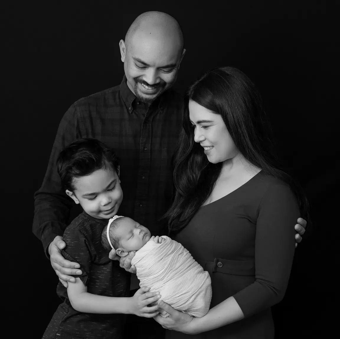 Newborn family photos Toronto – parents admiring and holding their newborn in soft studio lighting
