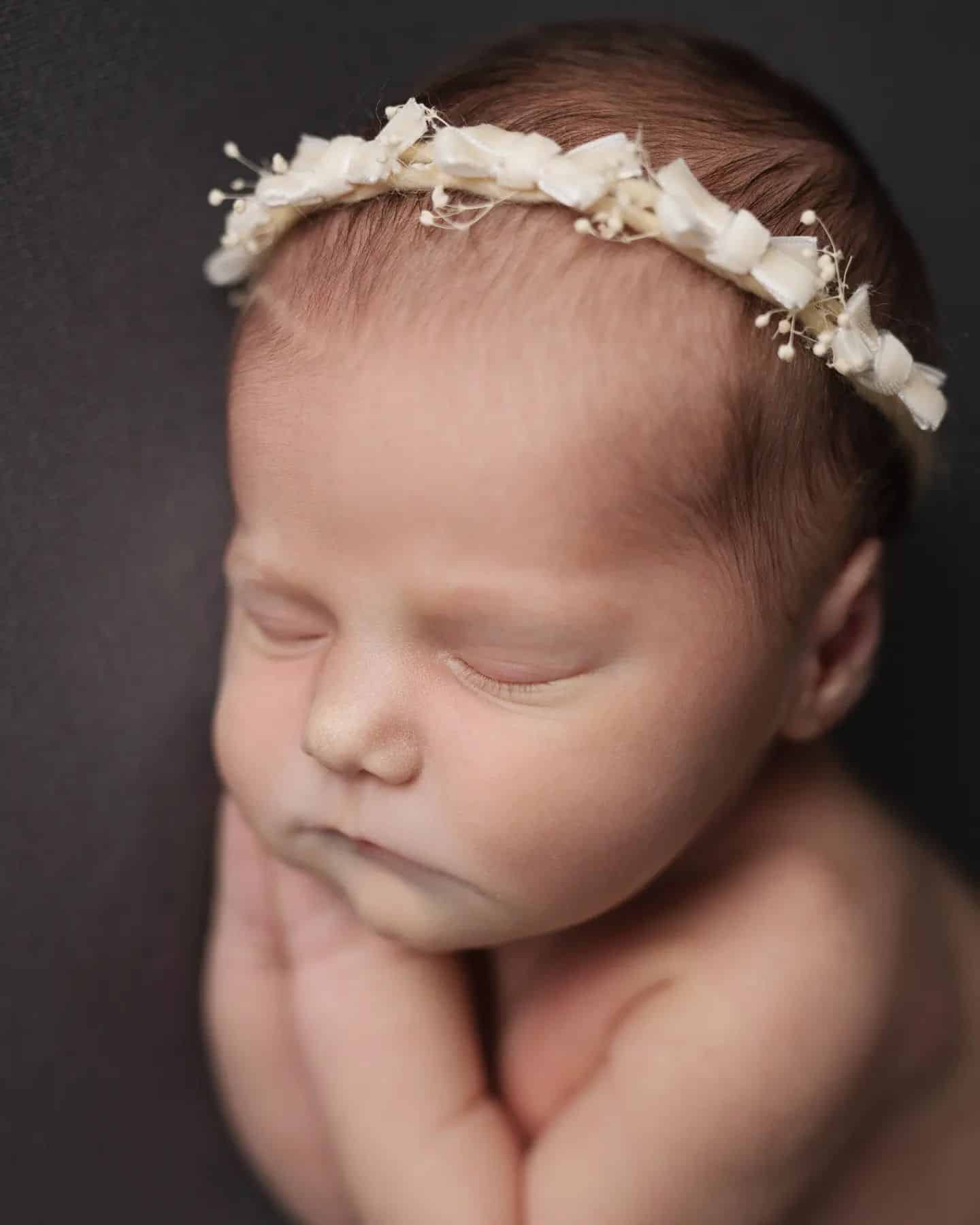 Studio newborn photography Toronto – peaceful sleeping baby wearing floral headband in warm tones