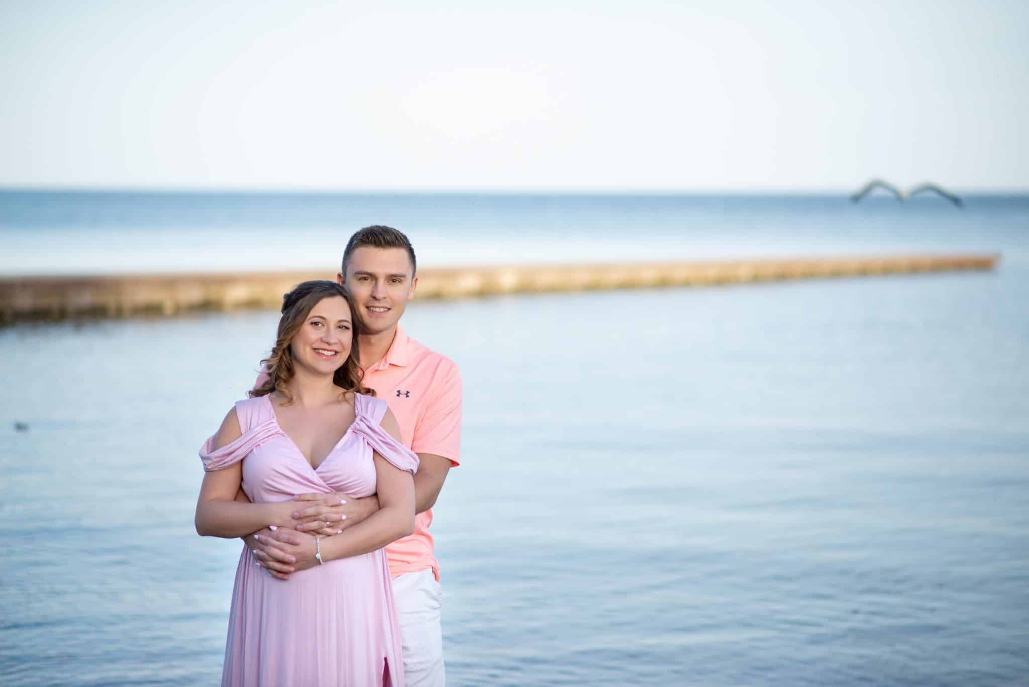 Intimate maternity couple portrait by the water, pregnancy photography Toronto, soft natural light outdoor expecting parents photoshoot.