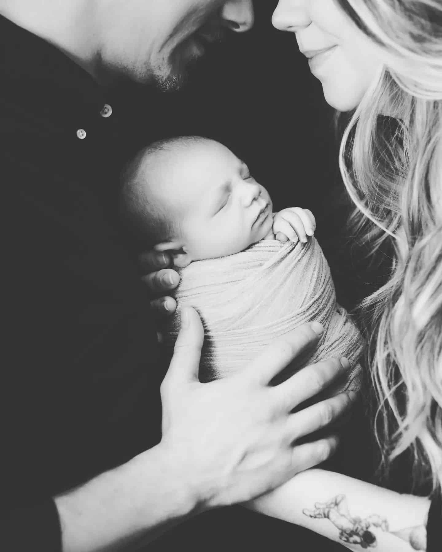 Black and white newborn family photos Mississauga showing loving parents holding their baby, an example of luxury newborn photography Mississauga