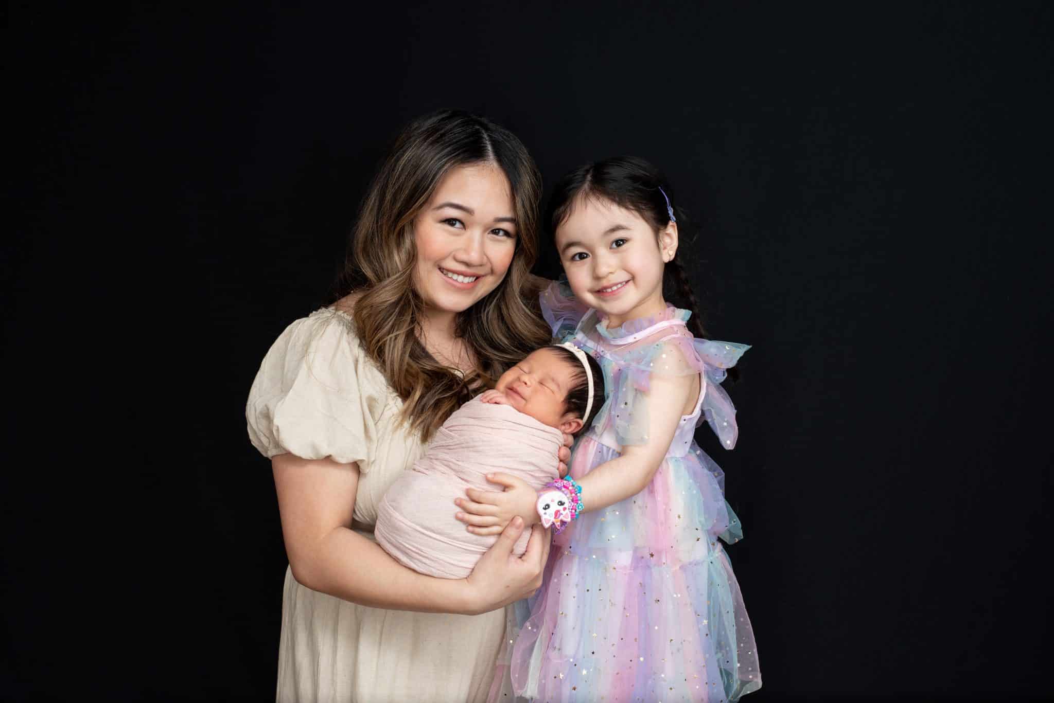 Mother and daughter holding their newborn baby during a timeless family newborn photography Toronto portrait