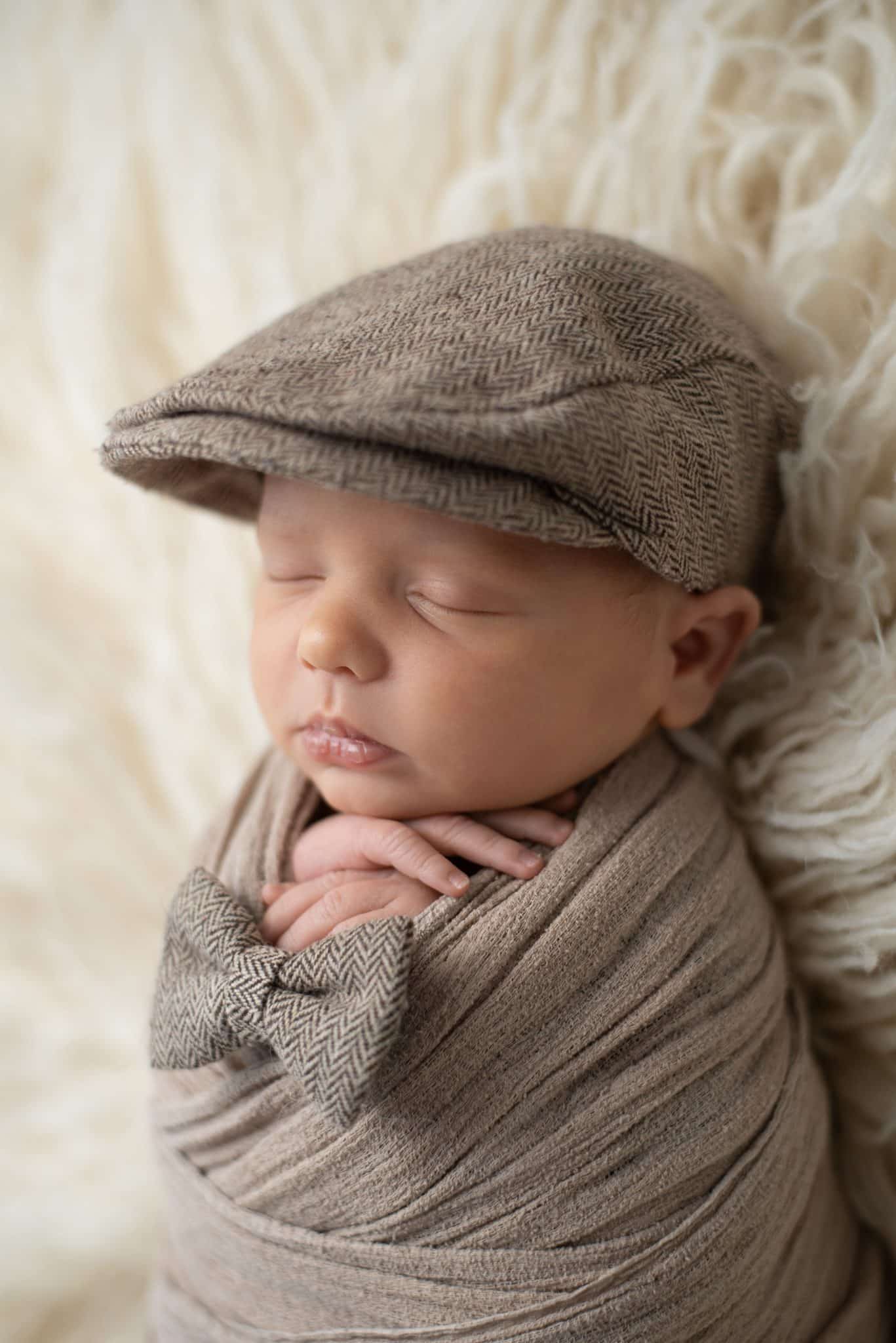 Sleeping newborn wearing a vintage cap during a cozy Toronto newborn photography session