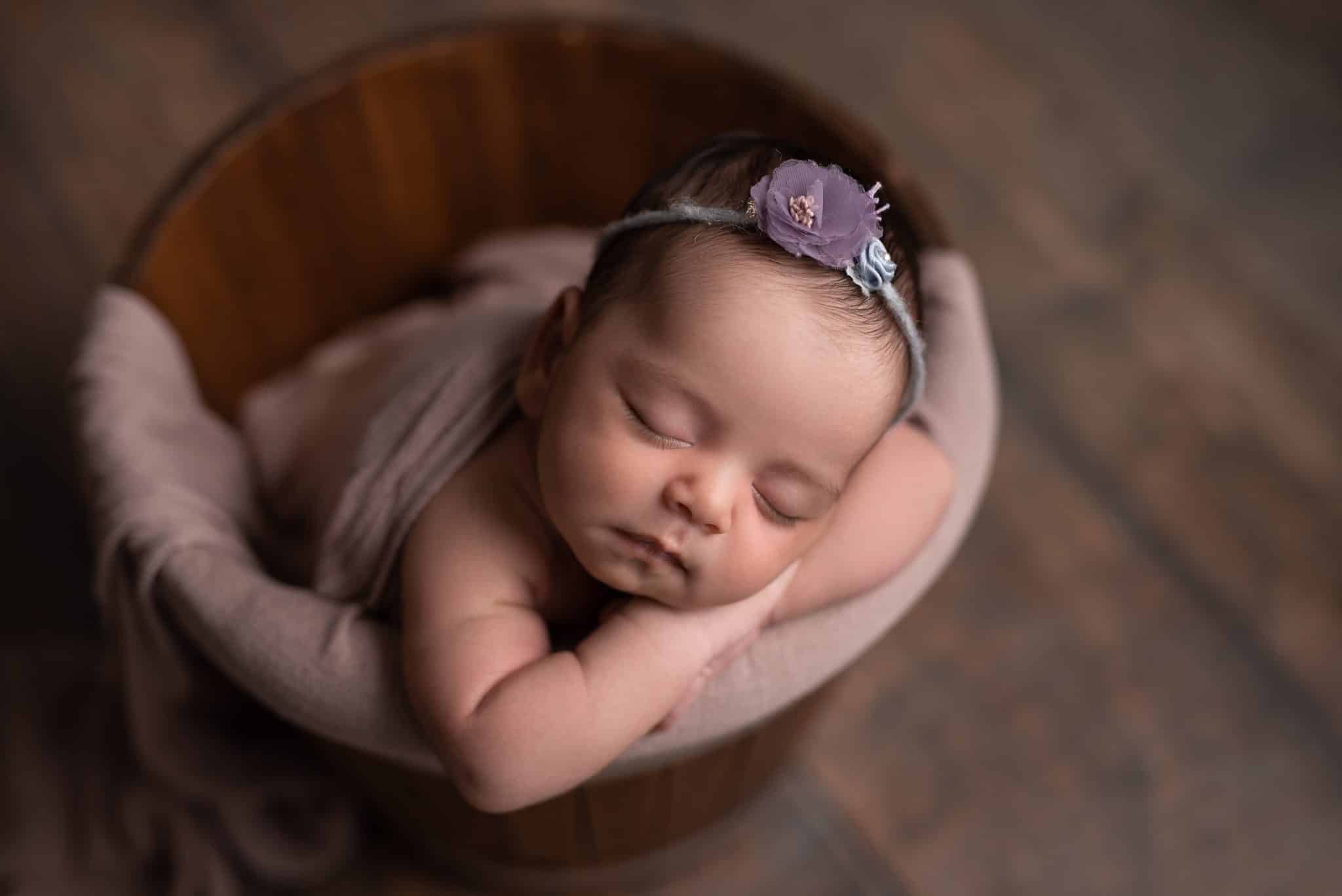 Sleeping baby girl posed in a wooden bucket during a professional Toronto newborn photography session