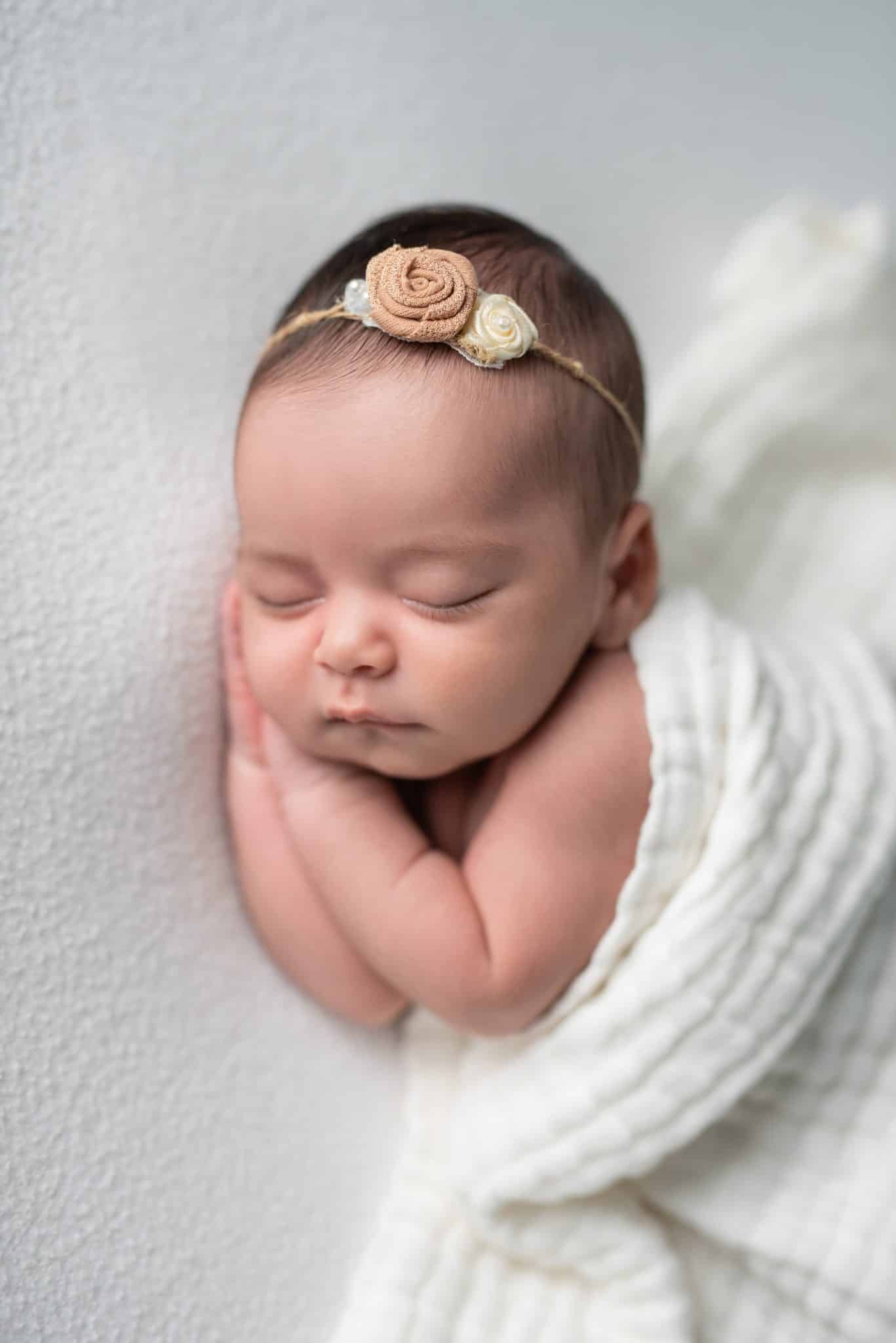 Soft and natural newborn portrait of a sleeping baby girl wrapped in white during a Toronto newborn photography session