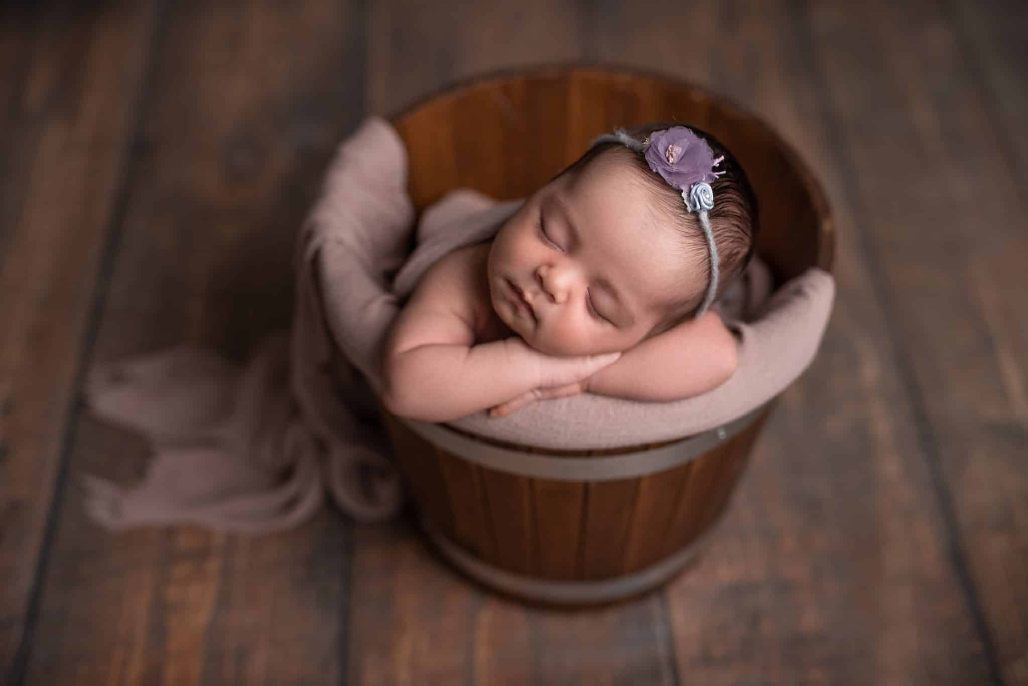 Peacefully sleeping newborn girl in a rustic bucket captured by a Toronto newborn photographer