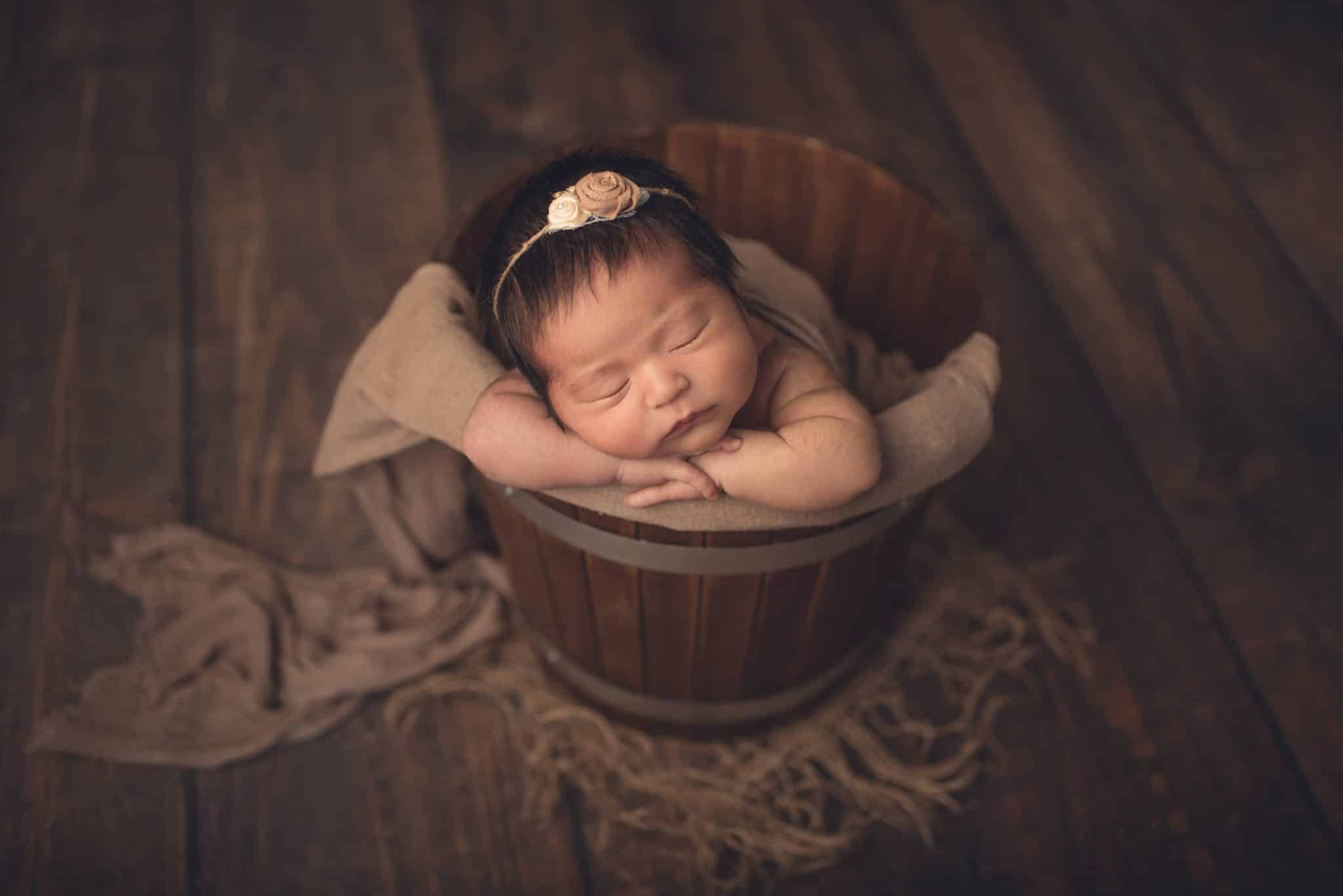 Newborn baby girl sleeping in the bucket during in-home newborn photoshoot in Toronto