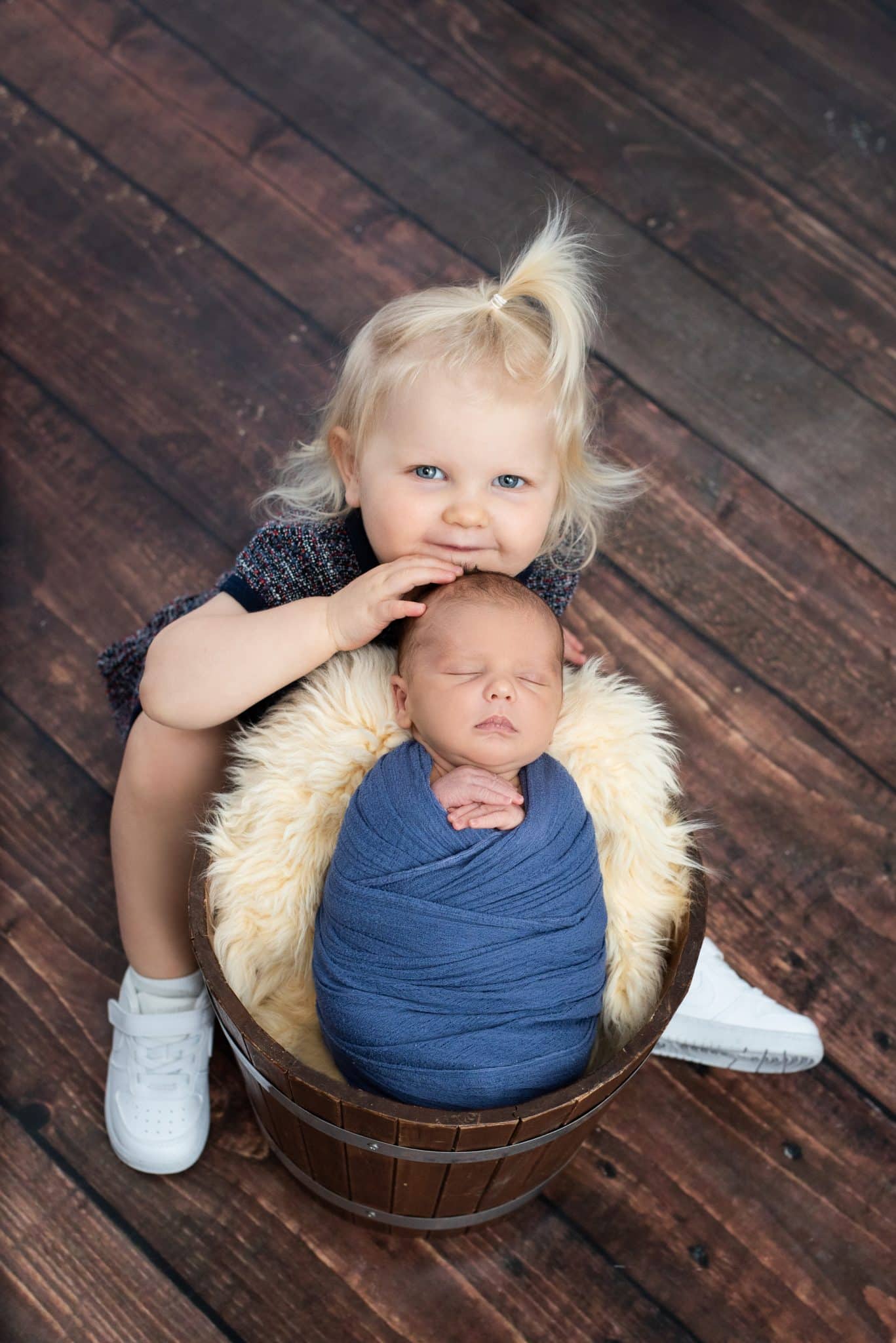 Toddler sitting beside newborn sibling during a natural family newborn photography Toronto session