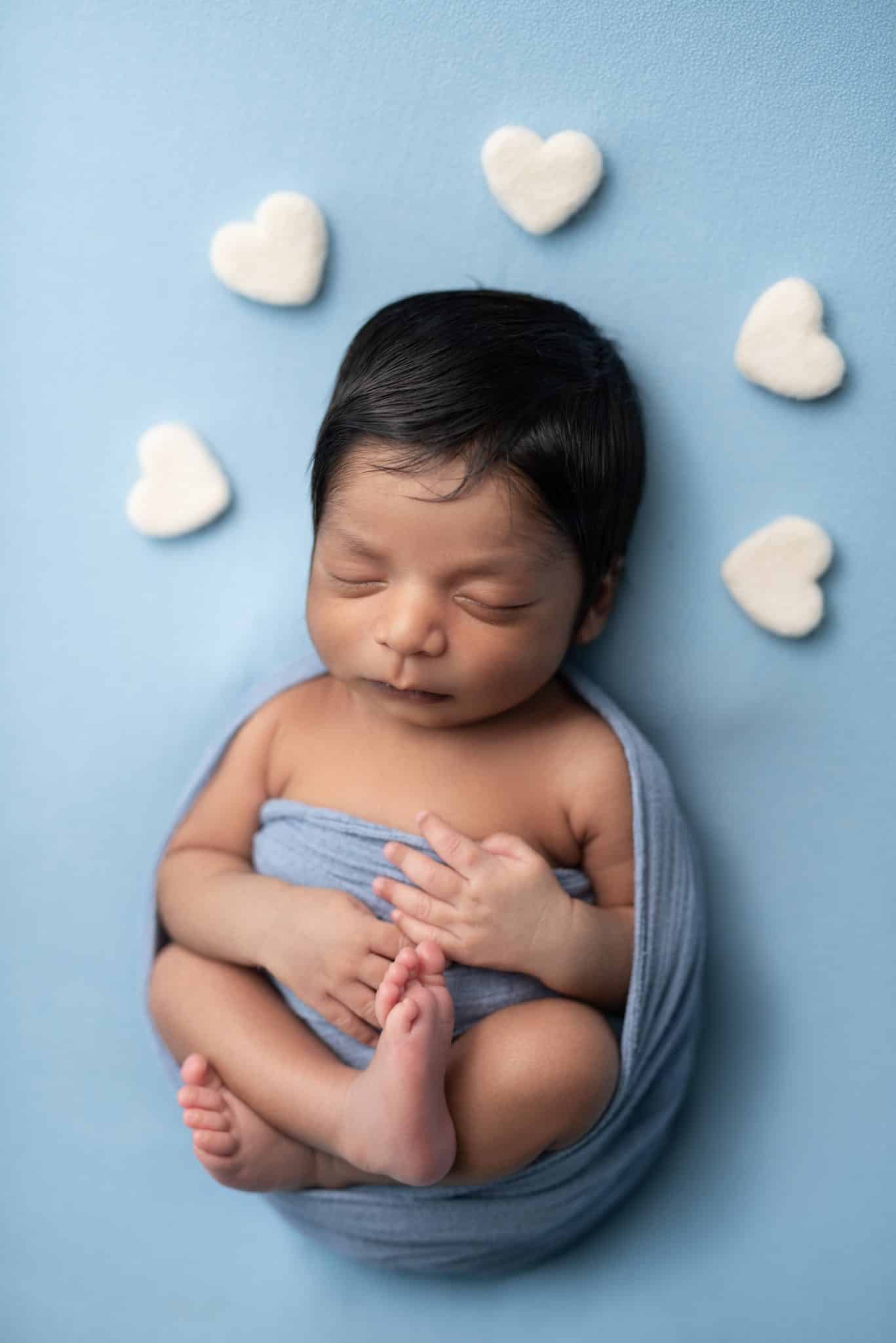 Lifestyle newborn photography Toronto – baby resting on soft blue backdrop with minimal props