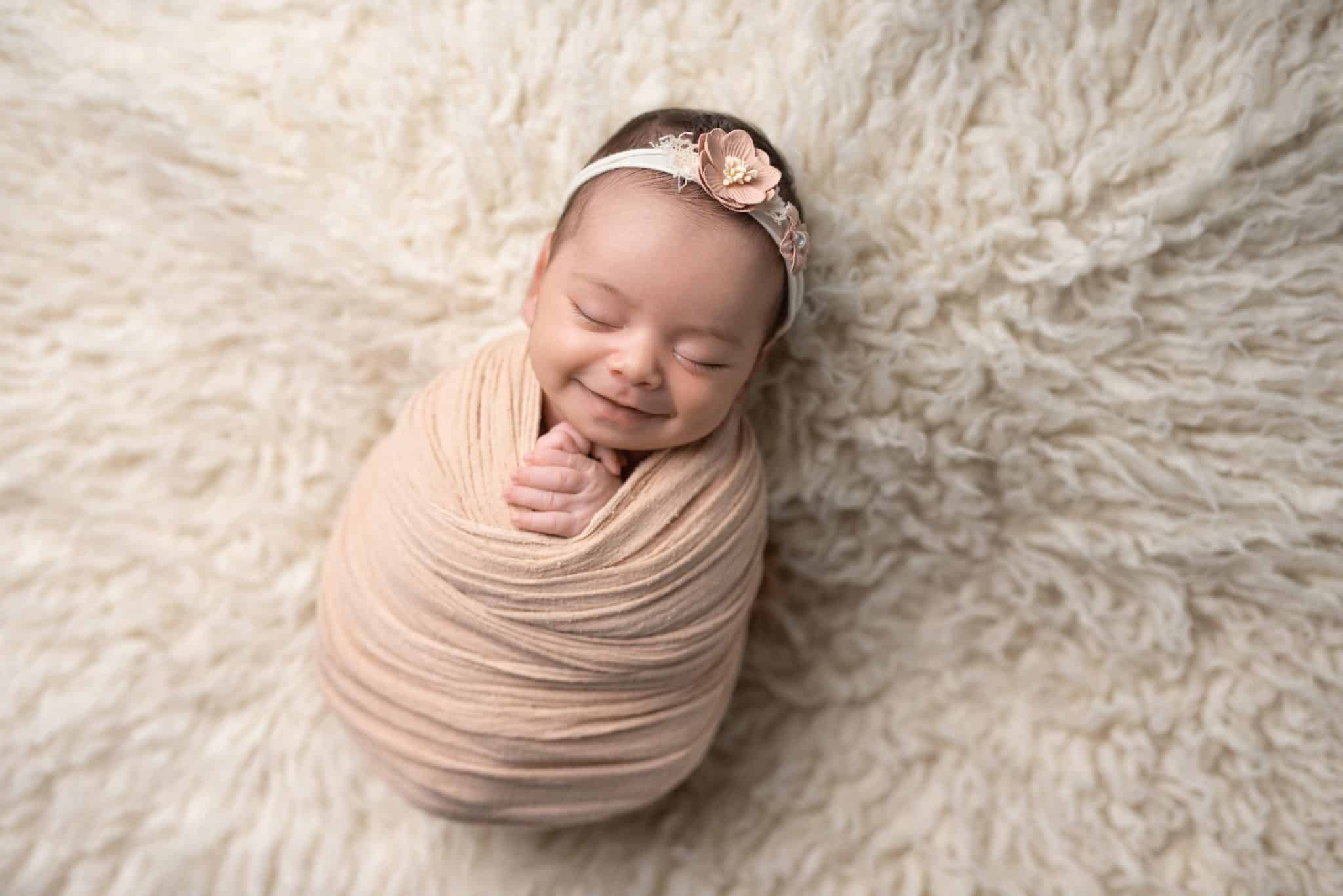 Wrapped newborn baby girl resting on a fluffy cream blanket photographed by a Toronto newborn photographer