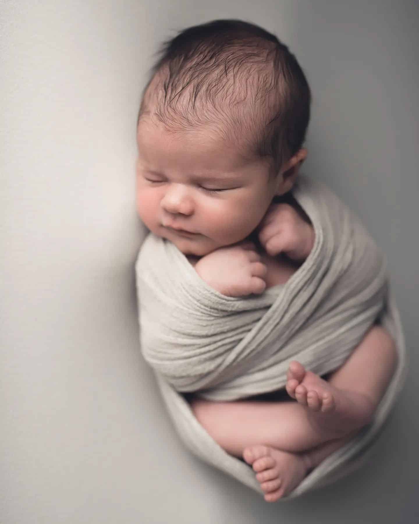 Peaceful sleeping baby wrapped in grey at a newborn photography studio Mississauga, showcasing beautiful baby photography Mississauga.