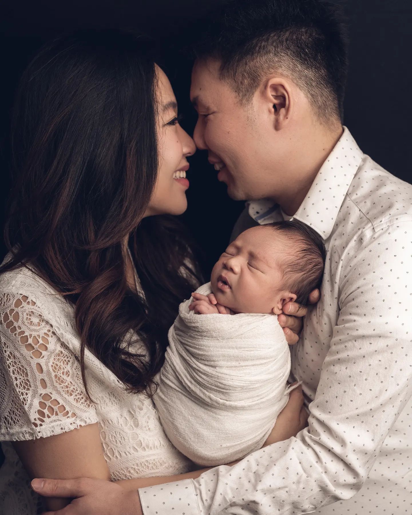 Happy parents holding their newborn baby during a newborn photo session Mississauga, offered by experts in maternity and newborn photography Mississauga